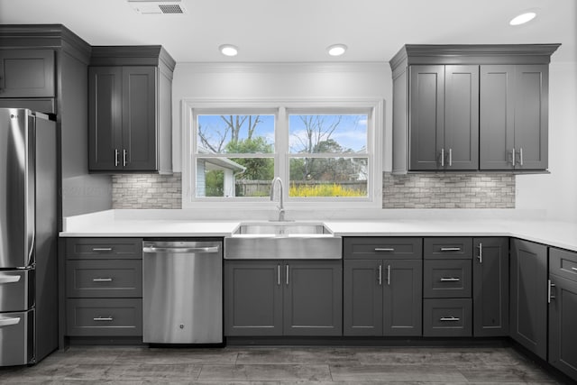 kitchen with crown molding, stainless steel appliances, gray cabinetry, a sink, and visible vents