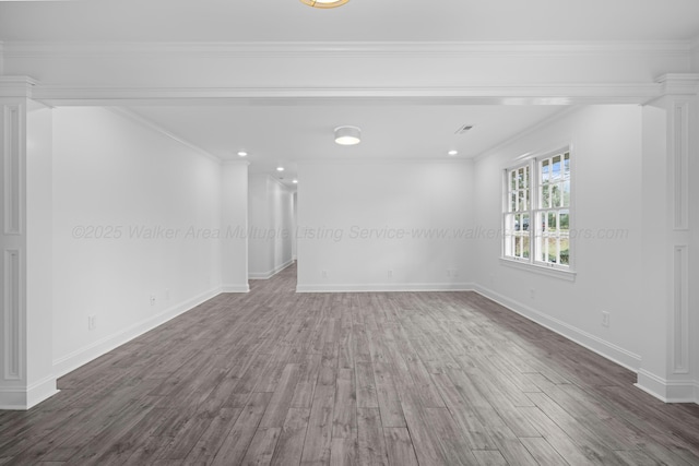 empty room with baseboards, decorative columns, crown molding, and wood finished floors