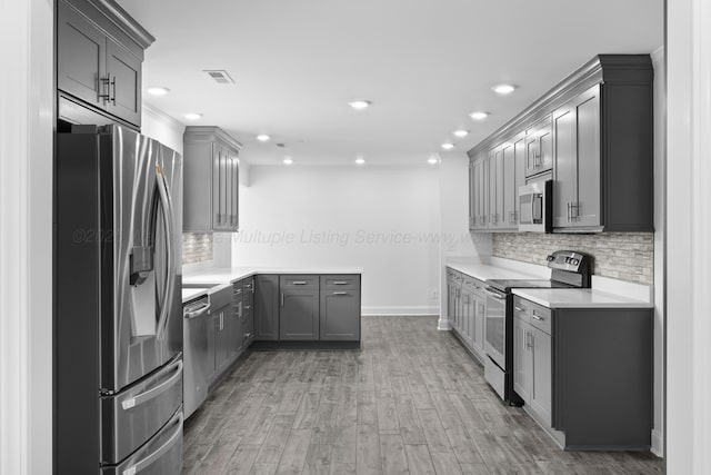 kitchen featuring light countertops, stainless steel appliances, gray cabinetry, light wood-style floors, and visible vents