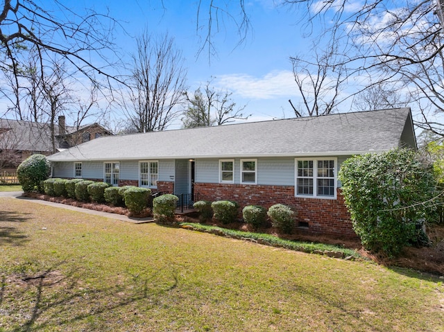 ranch-style home featuring a front lawn, crawl space, a shingled roof, and brick siding