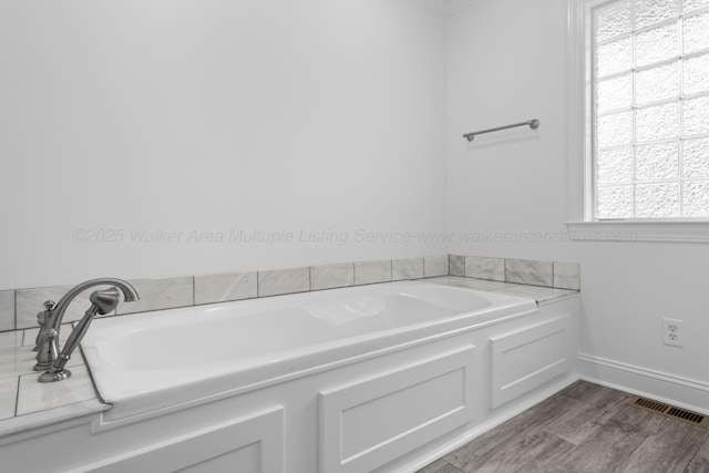 bathroom featuring wood finished floors, baseboards, a garden tub, and visible vents