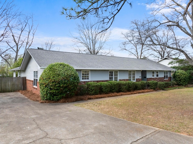 single story home featuring roof with shingles, brick siding, a front yard, and fence