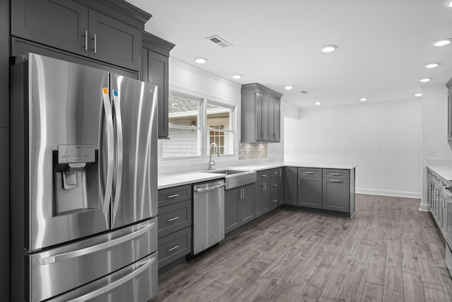 kitchen featuring visible vents, wood finished floors, stainless steel appliances, a sink, and gray cabinets