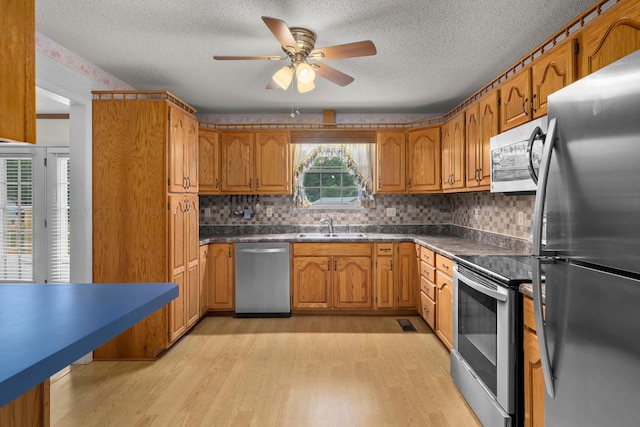 1768 Pineywoods Sipsey Rd, Jasper, AL 35504 - kitchen featuring stainless steel appliances, a textured ceiling, brown cabinetry, light wood-style floors, and dark countertops