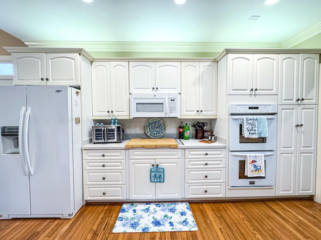 1000 Foothill Rd, Winfield, AL 35594 - kitchen featuring white appliances, light countertops, light wood-type flooring, decorative backsplash, and crown molding
