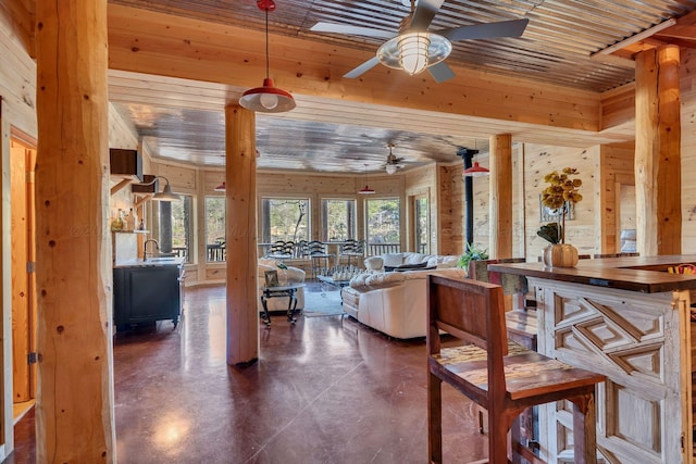 interior space featuring ceiling fan, concrete floors, and wooden walls