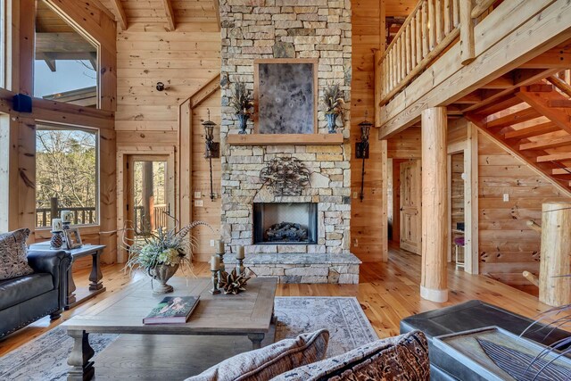 living area with a fireplace, high vaulted ceiling, wood walls, and hardwood / wood-style flooring