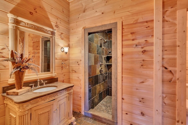 bathroom with wooden walls, vanity, and tiled shower