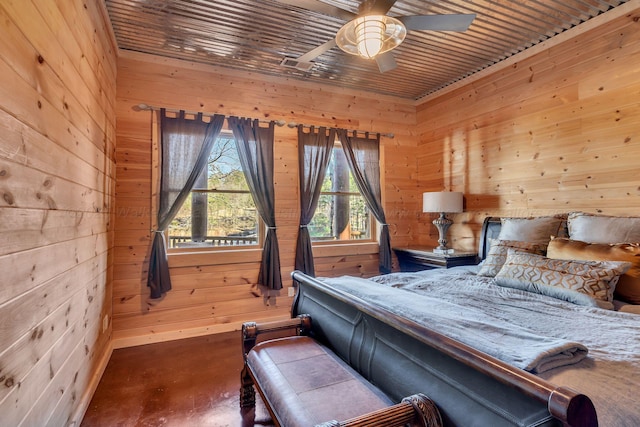 bedroom featuring wooden walls, concrete flooring, and a ceiling fan