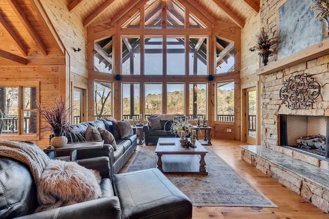 living area with beamed ceiling, wooden ceiling, a stone fireplace, and wood-type flooring