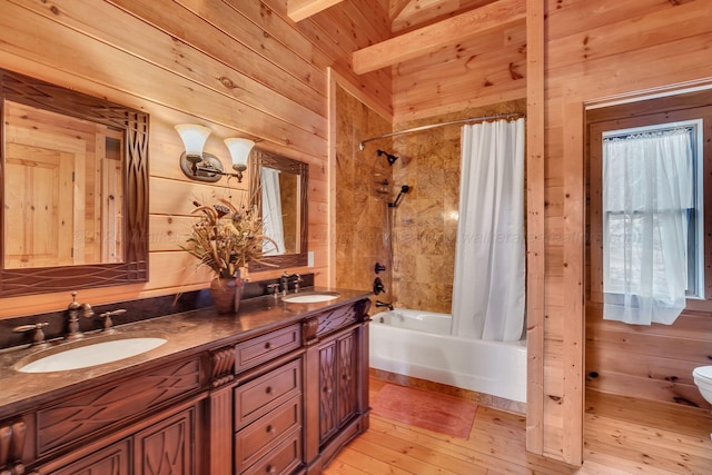 bathroom featuring a sink, wooden walls, double vanity, shower / tub combo, and toilet