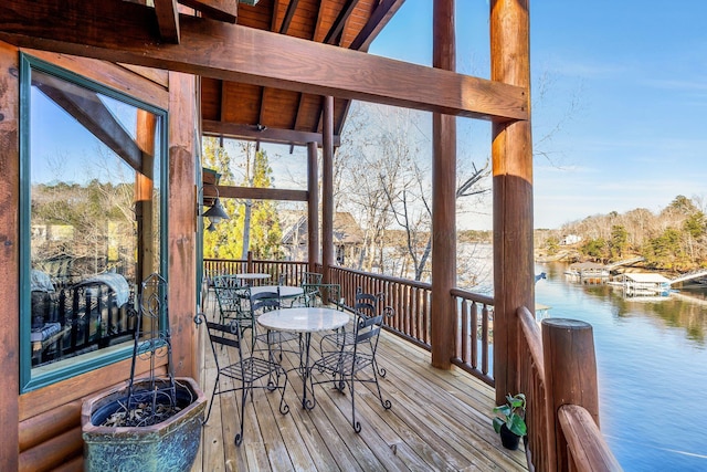 wooden terrace featuring outdoor dining area and a water view