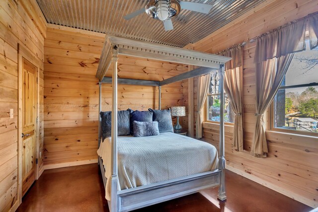 bedroom featuring concrete floors and wood walls