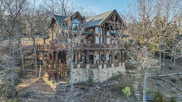 view of property exterior featuring a wooden deck, stone siding, and metal roof