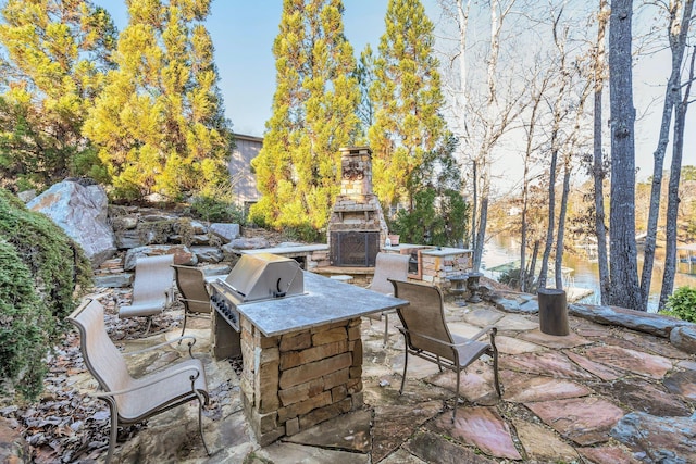view of patio / terrace with a grill, an outdoor stone fireplace, and area for grilling