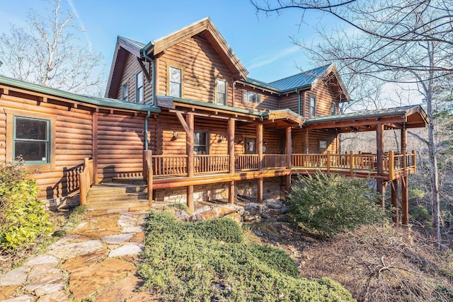 back of house with log exterior and a deck