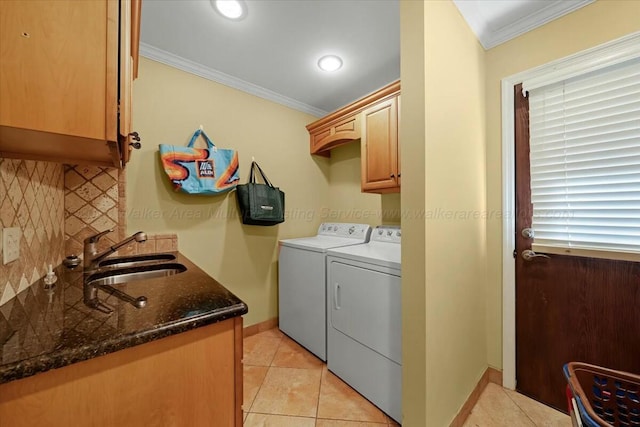 washroom featuring crown molding, light tile patterned floors, a sink, cabinet space, and washing machine and dryer
