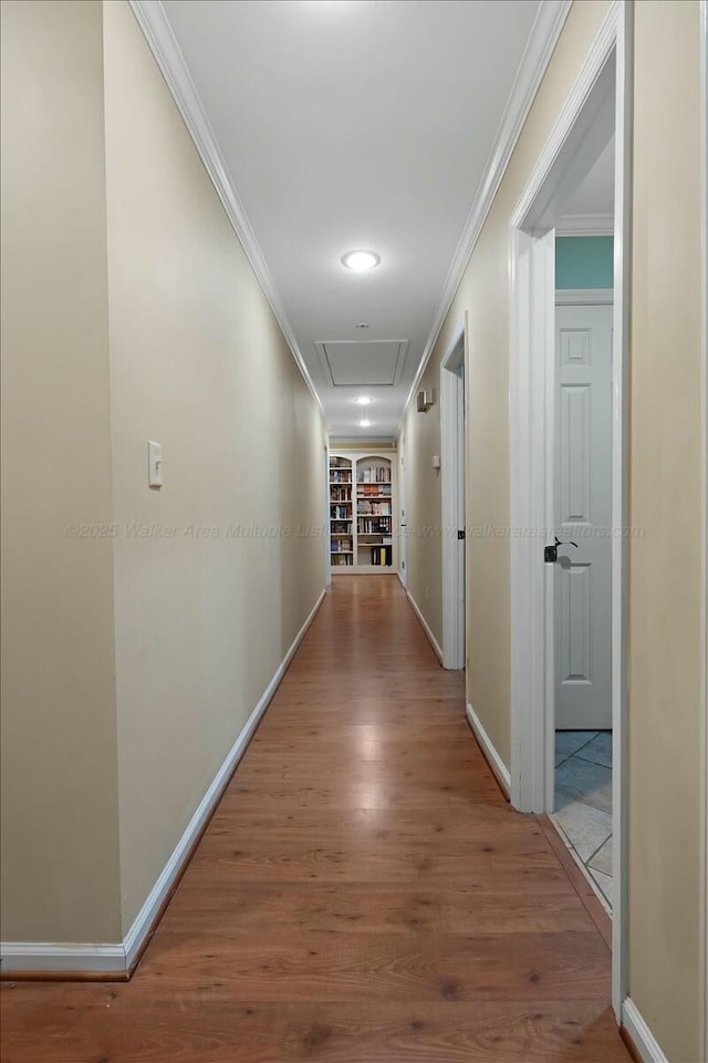 hall with baseboards, wood finished floors, and crown molding