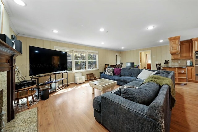 living area featuring crown molding, light wood-type flooring, a high end fireplace, and recessed lighting