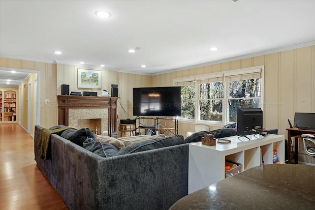 living area featuring a fireplace, wood finished floors, a decorative wall, ornamental molding, and recessed lighting