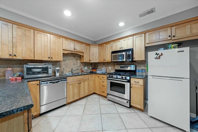 kitchen featuring visible vents, dark countertops, a sink, and stainless steel appliances