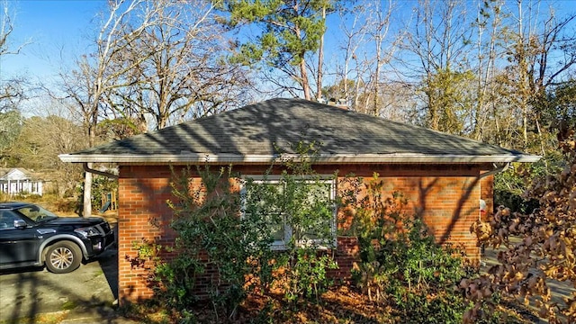 view of property exterior featuring brick siding and a shingled roof