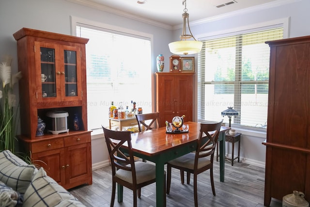 dining room featuring baseboards, visible vents, ornamental molding, and wood finished floors