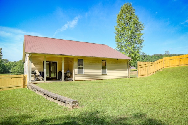 rear view of house featuring a fenced backyard, a yard, and metal roof