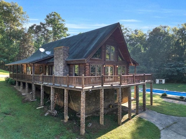 rear view of house featuring a wooden deck and a yard