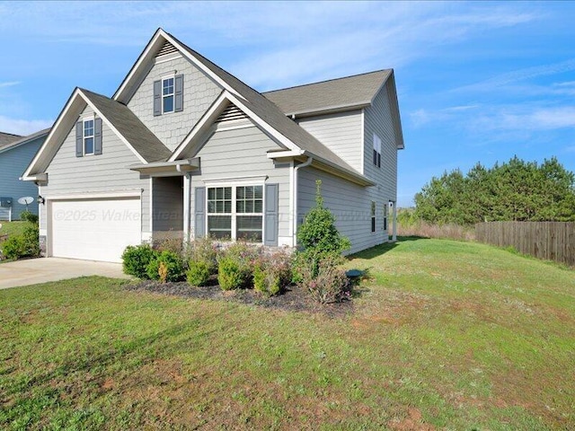 view of front of house with concrete driveway, a front lawn, fence, and an attached garage