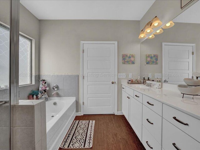 full bath featuring wood finished floors, a garden tub, and vanity