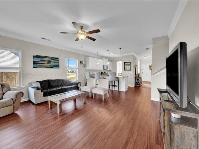 living area with crown molding, baseboards, ceiling fan, and dark wood finished floors