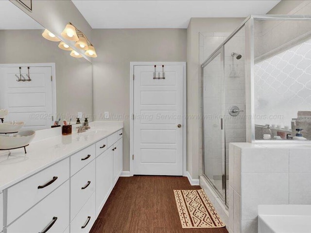 bathroom featuring vanity, wood finished floors, a bathtub, and a shower stall