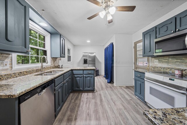 1812 N Walston Rd, Jasper, AL 35504 - kitchen featuring stainless steel appliances, light wood-style flooring, a ceiling fan, decorative backsplash, and a wainscoted wall