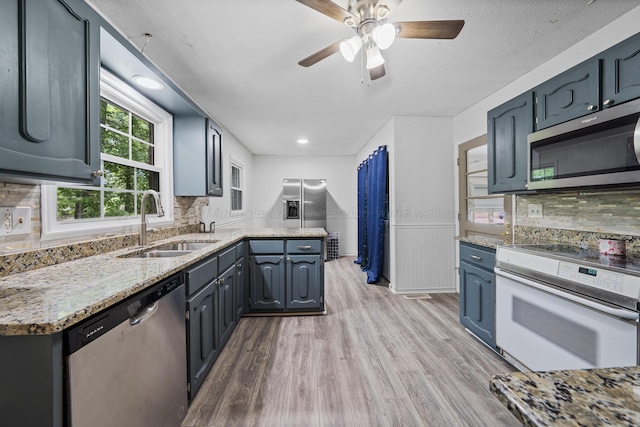 1812 N Walston Rd, Jasper, AL 35504 - kitchen featuring stainless steel appliances, light wood-style flooring, a ceiling fan, decorative backsplash, and a wainscoted wall