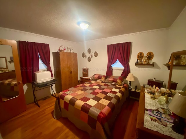 bedroom with a textured ceiling and wood finished floors