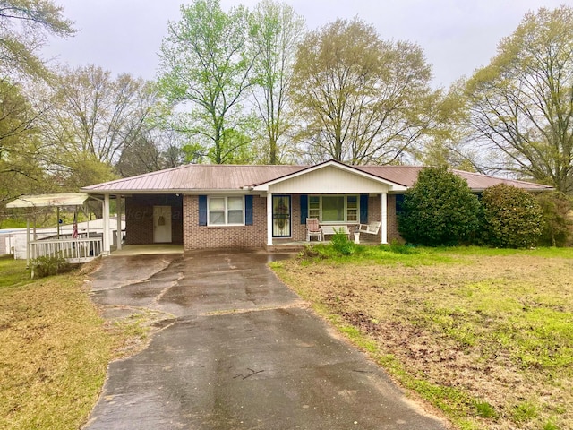 ranch-style house with aphalt driveway, a porch, a carport, a front lawn, and brick siding