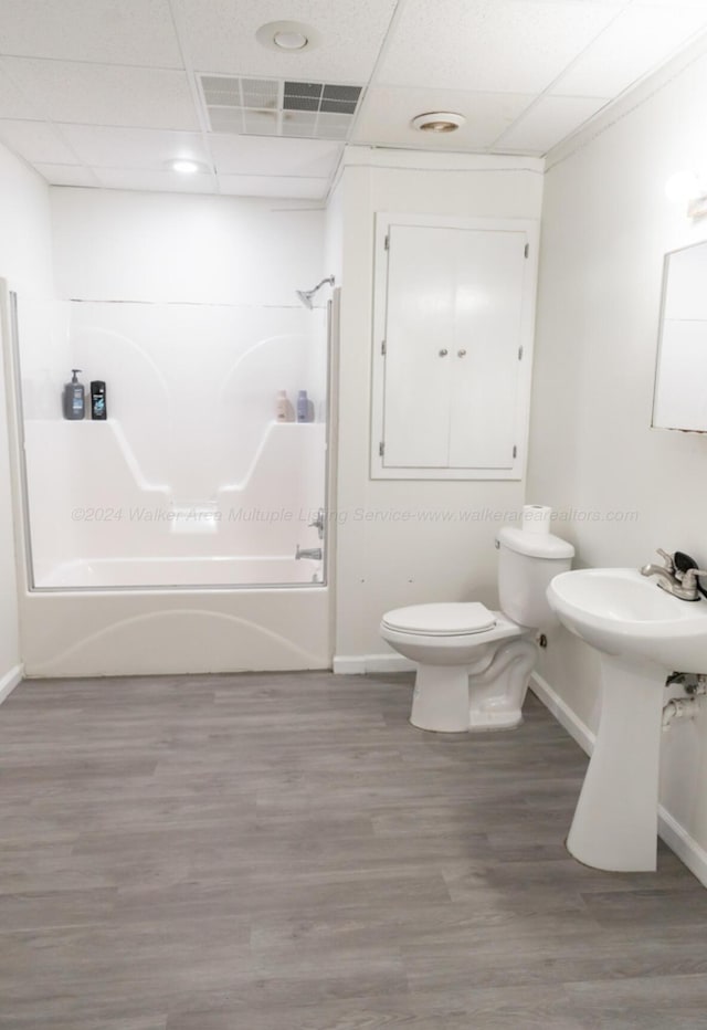 full bathroom with wood-type flooring, a paneled ceiling, toilet, and tub / shower combination