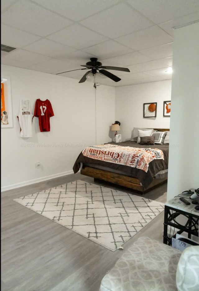 bedroom with a paneled ceiling, light hardwood / wood-style floors, and ceiling fan