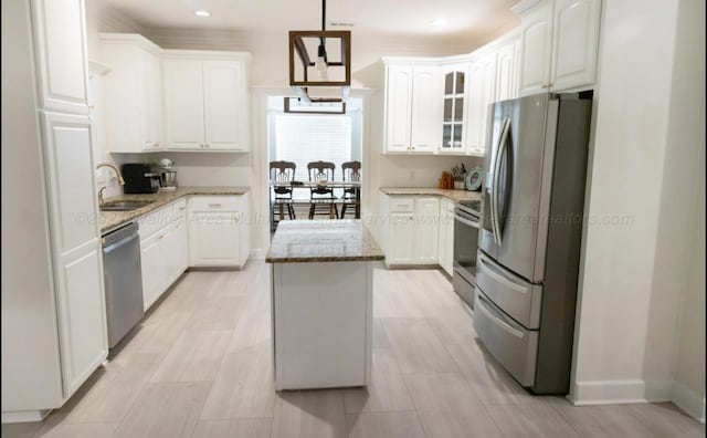 kitchen featuring hanging light fixtures, a center island, white cabinets, and stainless steel appliances