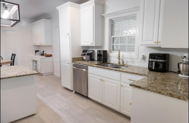 kitchen featuring white cabinets, stainless steel dishwasher, light stone countertops, and sink