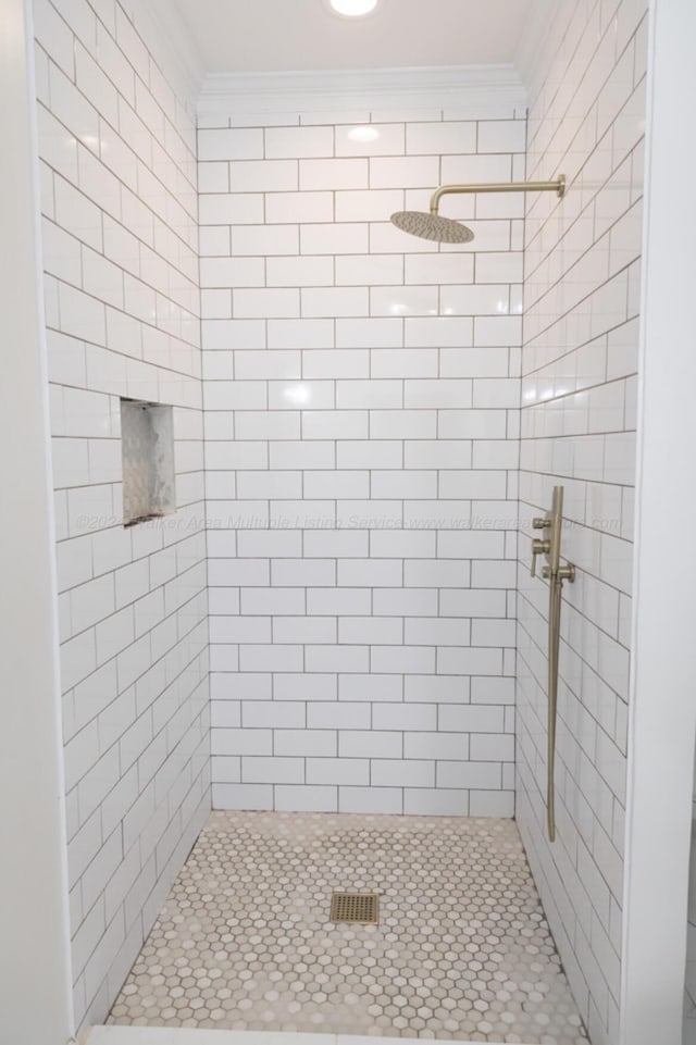 bathroom with ornamental molding and tiled shower