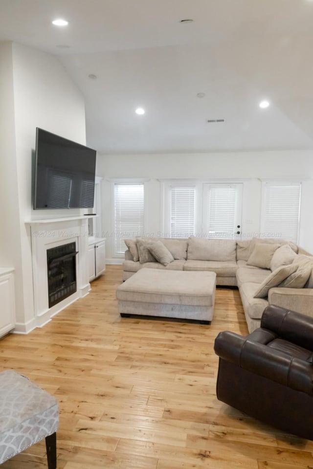 living room featuring lofted ceiling and light wood-type flooring