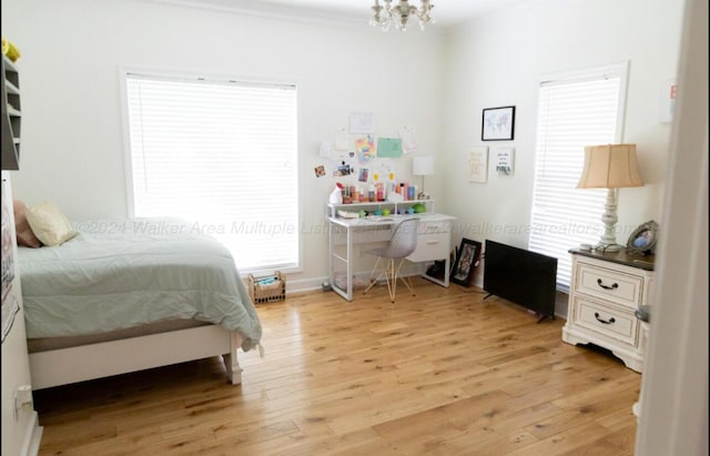 bedroom with a chandelier, light wood-type flooring, and multiple windows