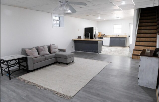 living room featuring a drop ceiling, a healthy amount of sunlight, and dark wood-type flooring