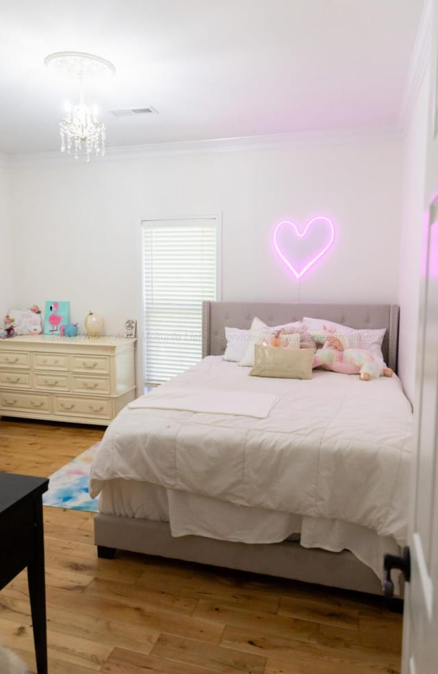 bedroom featuring ornamental molding, a notable chandelier, and light wood-type flooring