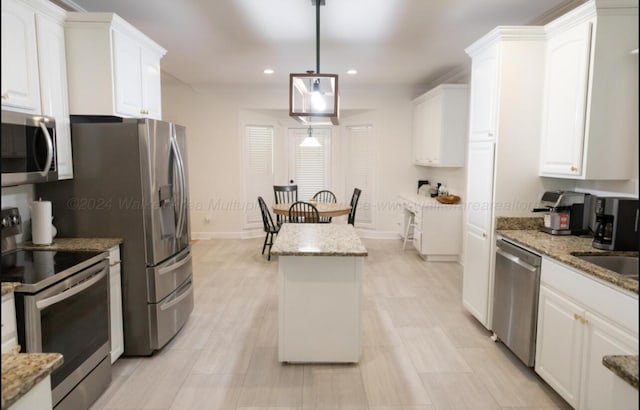 kitchen with pendant lighting, white cabinets, stainless steel appliances, and stone countertops