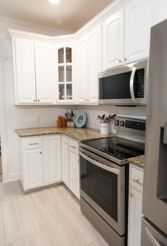 kitchen with white cabinets, stainless steel appliances, light stone counters, and crown molding