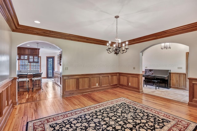 129 County Road 293, Cullman, AL 35057 - dining room with light wood-type flooring, a wainscoted wall, crown molding, arched walkways, and a chandelier