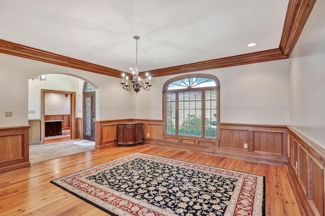 129 County Road 293, Cullman, AL 35057 - unfurnished dining area with wainscoting, light wood-style floors, arched walkways, ornamental molding, and a chandelier